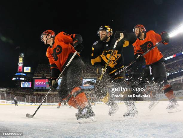 Philippe Myers and Justin Bailey of the Philadelphia Flyers battles atop the crease against Bryan Rust of the Pittsburgh Penguins at the 2019 Coors...