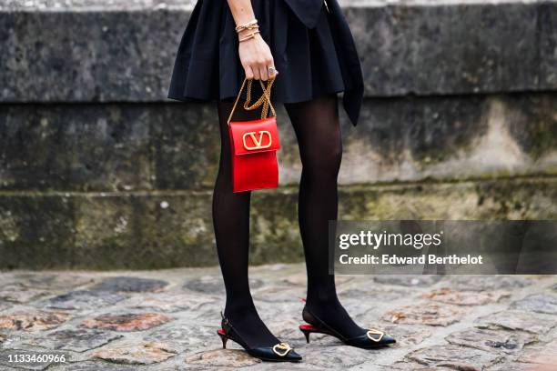 Caroline Daur a black gathered dress, a red Valentino bag, black Valentino pointy kitten heeled slingback pumps, black tights, outside Valentino,...