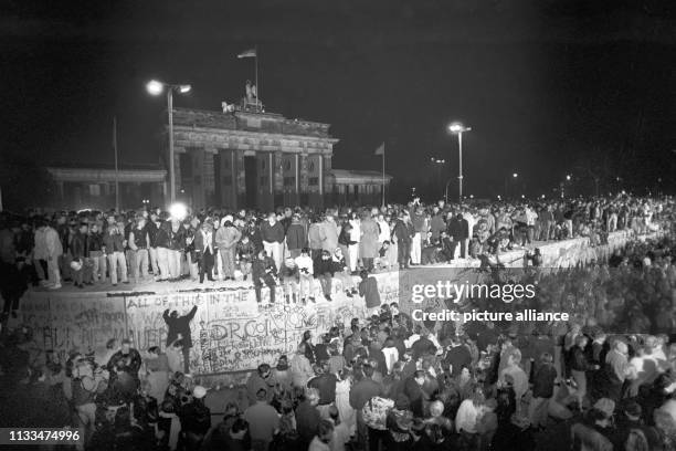 Menschen auf der Berliner Mauer vor dem Brandenburger Tor in der Nacht vom 9. Auf den . Vom , dem Tag des Mauerbaus, bis zum Mauerfall am waren die...
