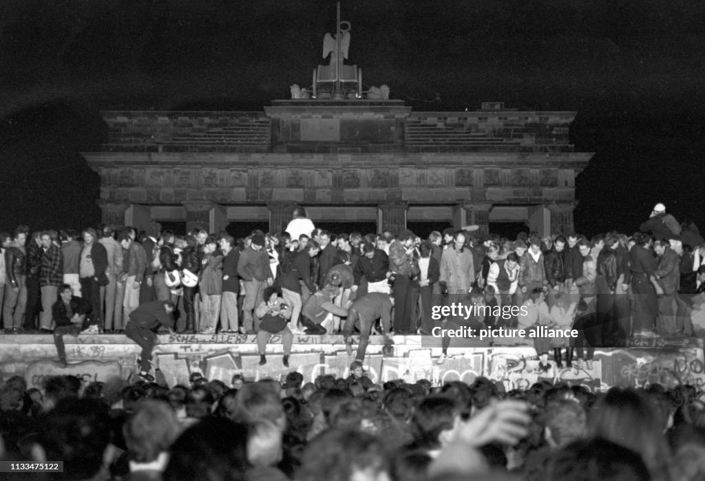 Jubelnde Menschen auf der Berliner Mauer am Brandenburger Tor in der ...