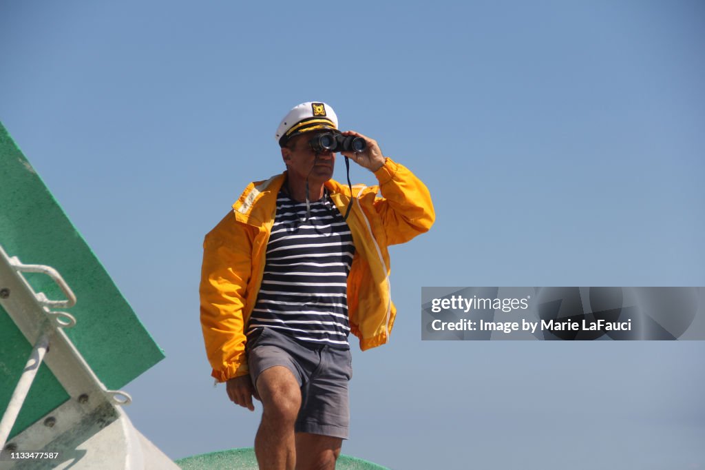 Boat captain looking through binoculars