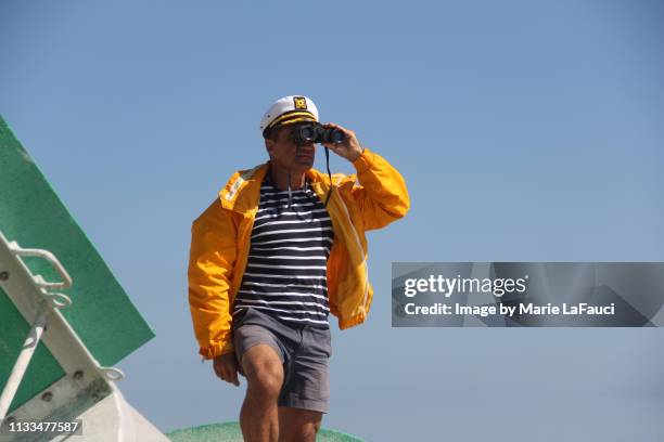 boat captain looking through binoculars - captain yacht stockfoto's en -beelden