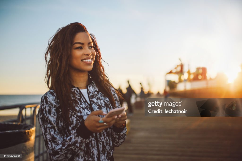 Young fashionable woman texting on her phone in Santa Monica, LA