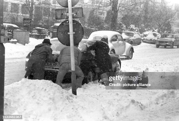 Hilfsbereite Passanten helfen einem Autofahrer durch anschieben des Fahrzeugs sich aus den Schneemassen zu befreien, aufgenommen am in Hamburg. Der...