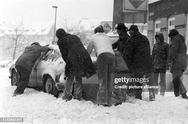 Hilfsbereite Passanten helfen einem Autofahrer durch anschieben des Fahrzeugs sich aus den Schneemassen zu befreien, aufgenommen am in Kiel. Der...