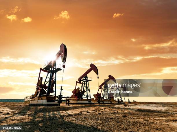 oil pumps working under the sunrise sky - working oil pumps stock pictures, royalty-free photos & images
