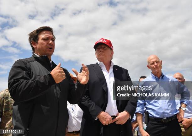 President Donald Trump and Florida Republican US Senator Rick Scott listen to Florida Governor Ron DeSantis during a tour of the Edgar Hoover Dike on...