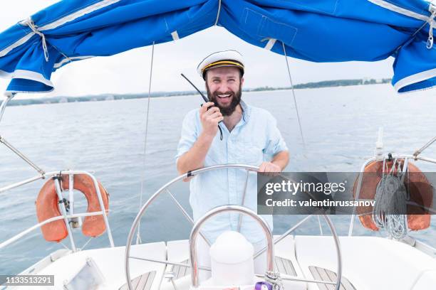 captain talking on walkie-talkie and sailing - boat captain stock pictures, royalty-free photos & images