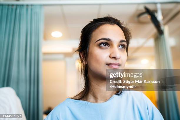 thoughtful female patient looking away in ward - examination gown stock pictures, royalty-free photos & images