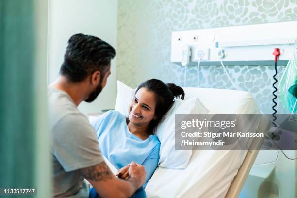 glimlachende vrouwelijke patiënt te kijken naar de mens in het ziekenhuis - hospital bed stockfoto's en -beelden