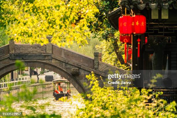 boatman rowing on canal travel through an arch bridge - suzhou china fotografías e imágenes de stock