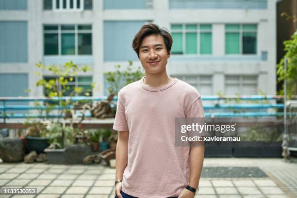 portrait of smiling young man on terrace in city - asian man portrait stock pictures, royalty-free photos & images