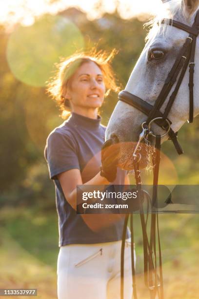 mid adult woman caring for horse - racehorse owner stock pictures, royalty-free photos & images