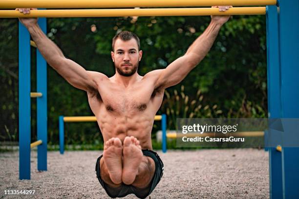 young man doing l-sit exercise outdoors - gymnastics bar stock pictures, royalty-free photos & images