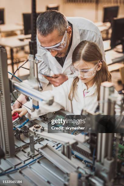 männliche laborarbeiter, die kleine mädchen über maschinenteile im labor lehren. - science lab school stock-fotos und bilder
