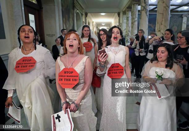 Demonstrators march down the hallway towards Governor Charlie Baker's office wearing bridal gowns and veils during a protest urging legislators to...