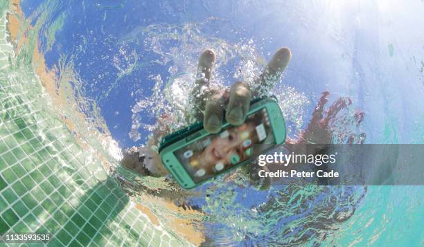 dropping mobile phone in pool - swimming pool and hand stock-fotos und bilder