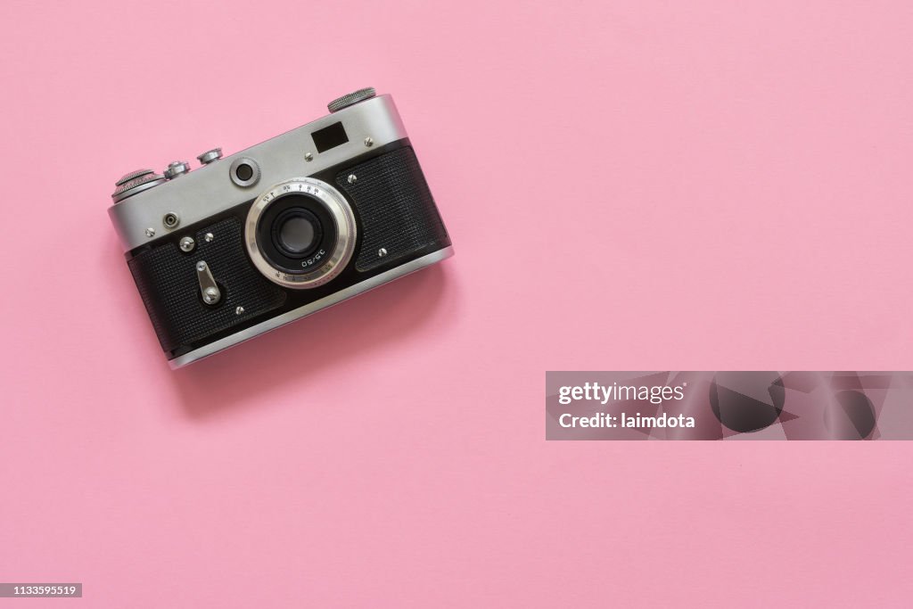 Flatlay Vintage-Retro-Kamera auf rosa Hintergrund. Kopierplatz, obere Ansicht