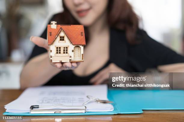 real estate concept; estate sale woman agent giving home model - model building stock-fotos und bilder