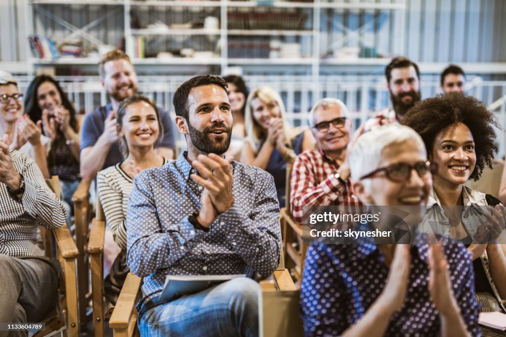 Large group of entrepreneurs applauding their colleague after seminar in board room.