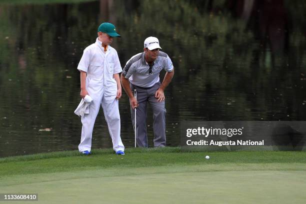 Kevin Streelman and his caddie Ethan Couch line up a putt on the No. 9 green during the Par 3 Contest for the Masters at Augusta National on...