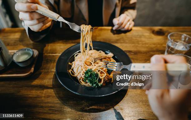 hands of couple sharing and enjoying freshly made pasta in a restaurant - coppie cibo food bistrot foto e immagini stock