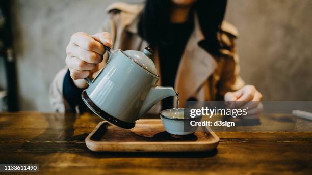woman enjoying a quiet moment with a fresh cup of tea in cafe - kräutertee stock-fotos und bilder
