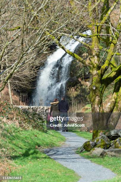 two adults and two children visiting a waterfall in a rural setting - galloway forest park stock pictures, royalty-free photos & images