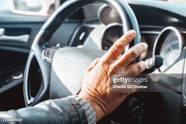 senior adult's hand on the steering wheel - driving stock pictures, royalty-free photos & images