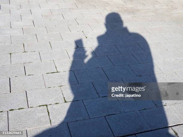 shadow of a man consulted the smartphone. - teléfono inteligente stock pictures, royalty-free photos & images