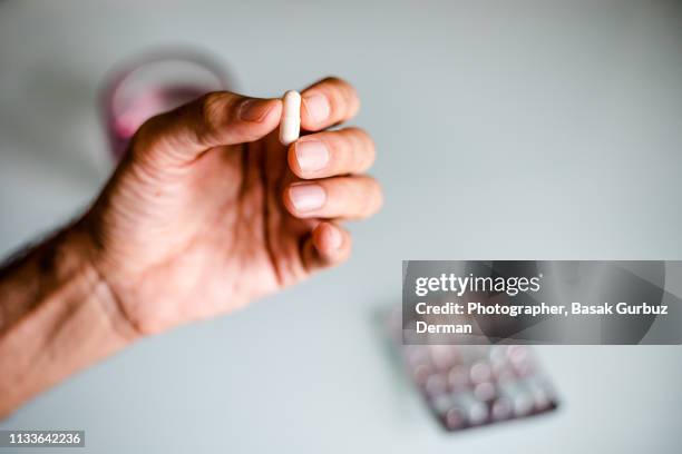 a man's hand holding a capsule / pill - doping ストックフォトと画像