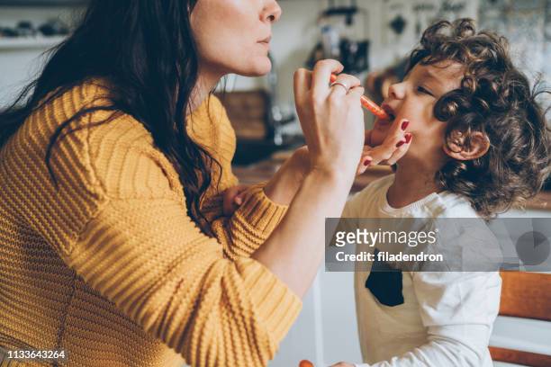 mother giving syrup to her son - hand over mouth stock pictures, royalty-free photos & images
