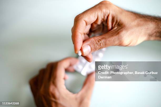 a man's hand holding a pill - prozac fotografías e imágenes de stock
