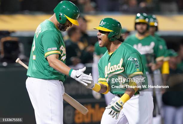 Khris Davis of the Oakland Athletics is congratulated by Kendrys Morales after Davis hit a two-run homer against the Los Angeles Angels of Anaheim in...
