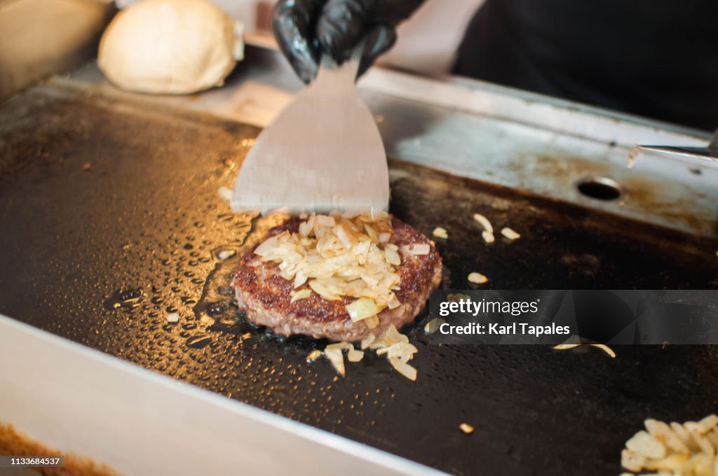 A chef is cooking a burger