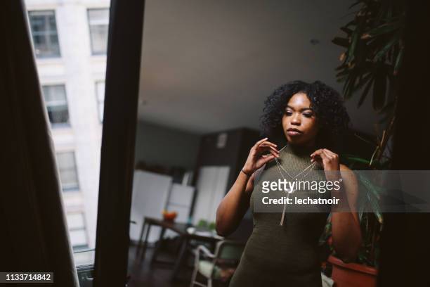 young woman at her apartment getting ready to go out - woman getting dressed stock pictures, royalty-free photos & images