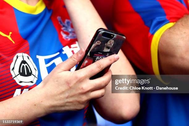 Crystal palace fan holds a phone with Luka Milivojevic on it during the Premier League match between Crystal Palace FC and Huddersfield Town at...