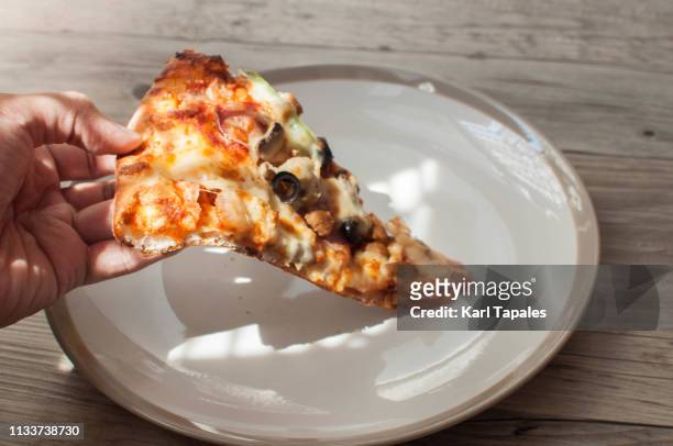 high-angle view of a slice of pizza on a white plate - pizza crust stock pictures, royalty-free photos & images