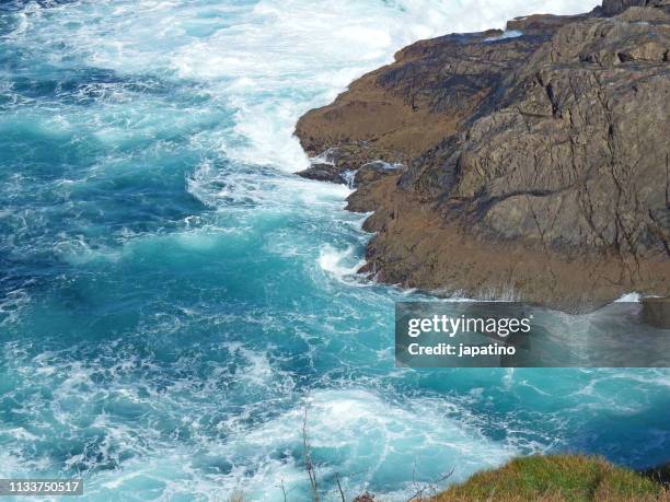 waves breaking against the rocks - fuerzas de la naturaleza stock pictures, royalty-free photos & images