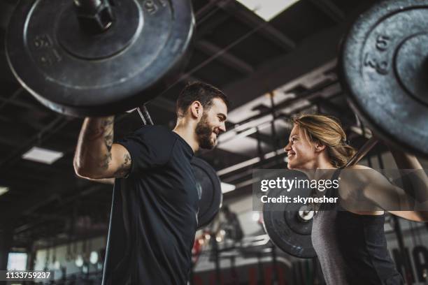 below view of athletic couple exercising with barbells in a gym - snatch weightlifting stock pictures, royalty-free photos & images