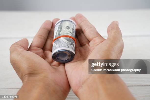 asian hand holding rolled dollar - 100 dollar bill new stockfoto's en -beelden