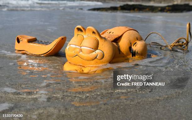 Plastic 'Garfield' phone is displayed on the beach on March 30, 2019 in Le Conquet, western France. - For more than 30 years, plastic phones in the...