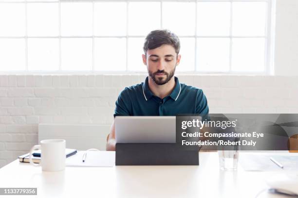 businessman using laptop in office - vanguardians stock-fotos und bilder