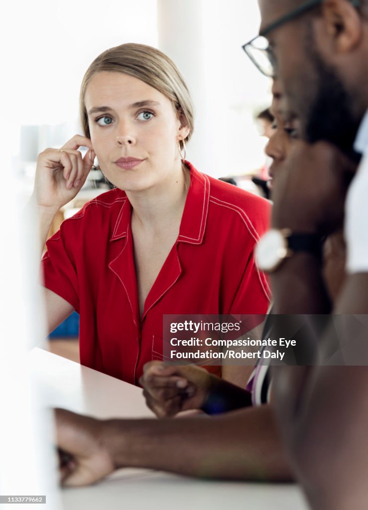 Businesswoman listening to colleagues in meeting