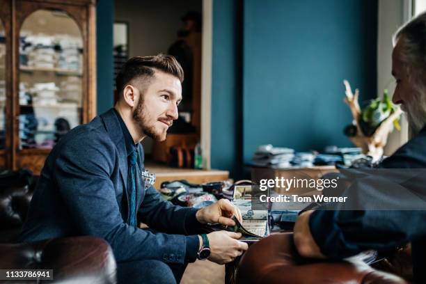 menswear store clerk helping customer with fabric swatches - tailor made ストックフォトと画像