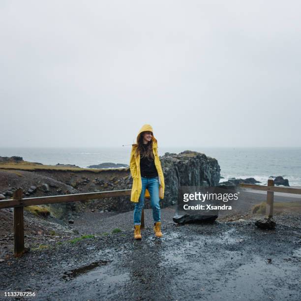 junge frau spaziert an einem regnerischen tag am strand - wet jeans stock-fotos und bilder