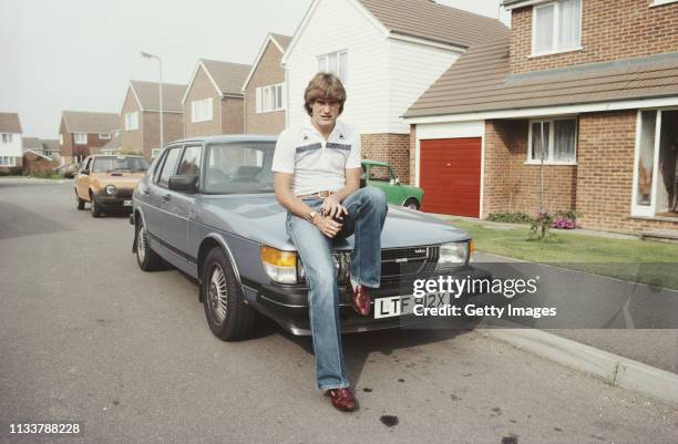 Tottenham Hotspur and England footballer Glenn Hoddle pictured sitting on the bonnet of his Saab motor car during an at home feature in September...