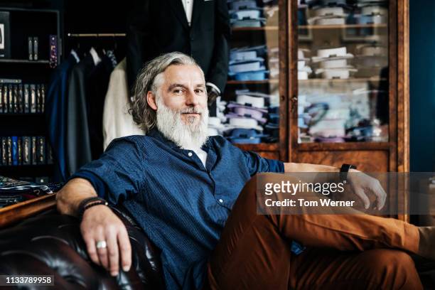portrait of customer relaxing in menswear store - barba peluria del viso foto e immagini stock