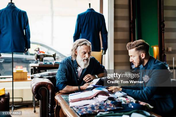 tailor looking at fabric swatches with customer - macchina per cucire foto e immagini stock
