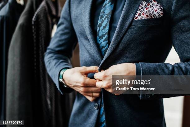 close-up of man buttoning up suit - pak stockfoto's en -beelden